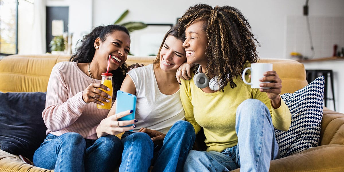 Three young people hanging out on a sofa