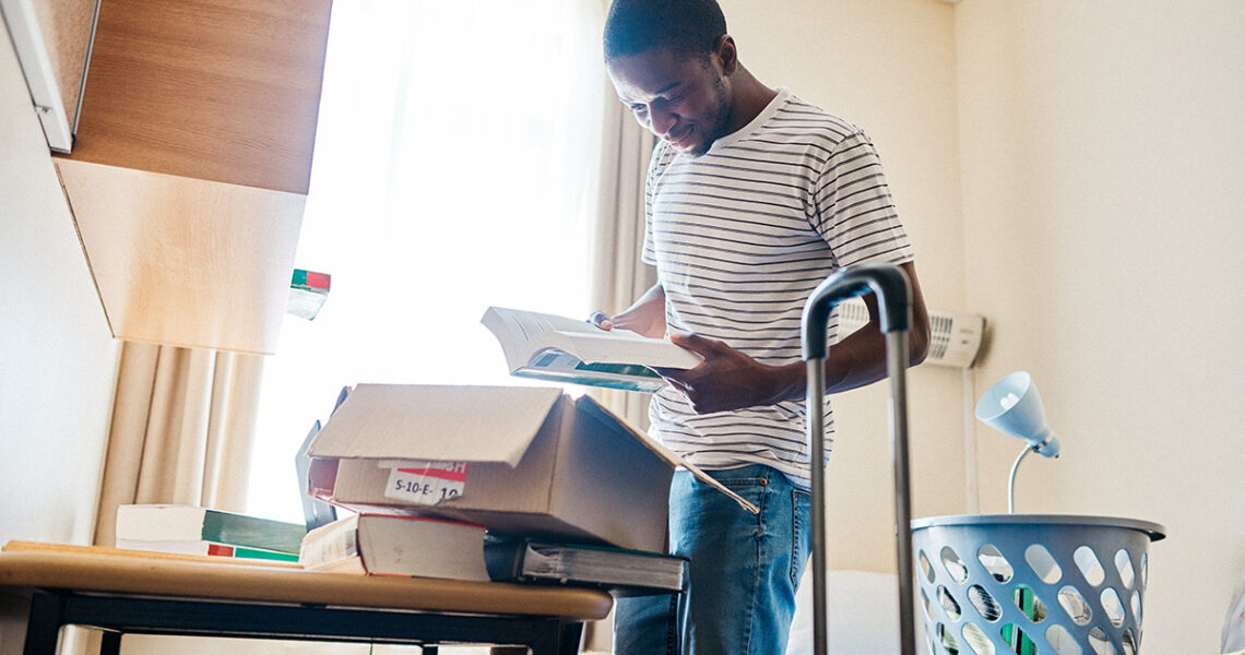 Young person standing in their dorm room unpacking