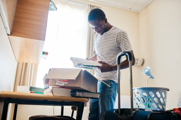 Young person standing in their dorm room unpacking